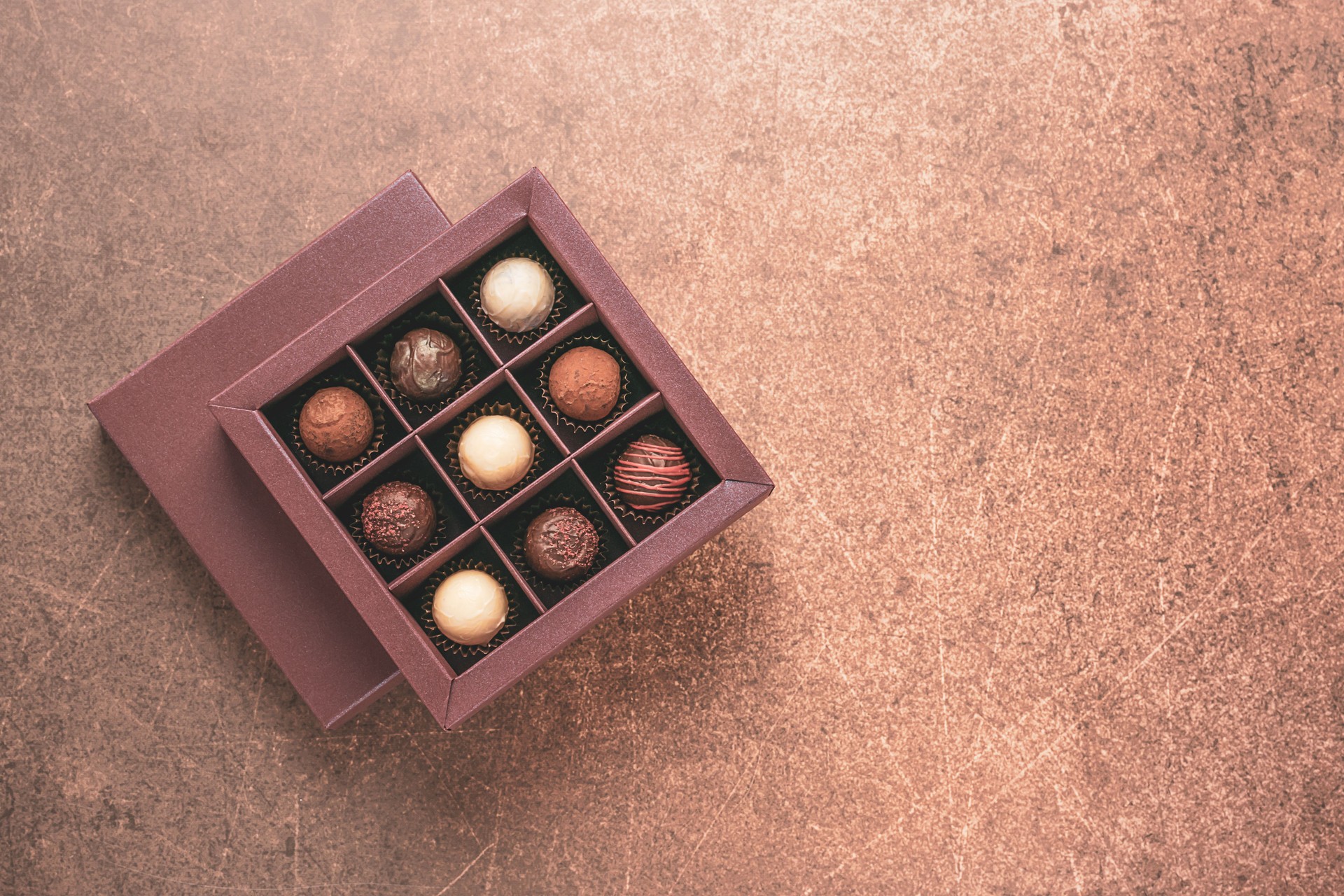 Handmade candies in a brown box on dark background. Flat top view. Copy space food holiday concept. Horizontal frame